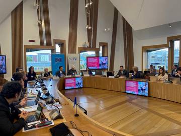 Dvorana, kjer je potekala konferenca. Vidni so udeleženvi za omizjem.