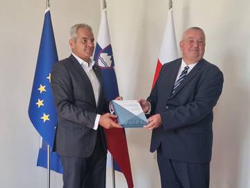 Župan Maribora Saša Arsenovič in namestnik varuha Ivan Šelih pred zastavami držita letno poročilo Varuha