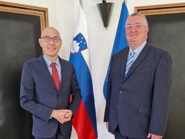 Volker Türk in Ivan Šelih stojita pred slovensko in evropsko zastavo