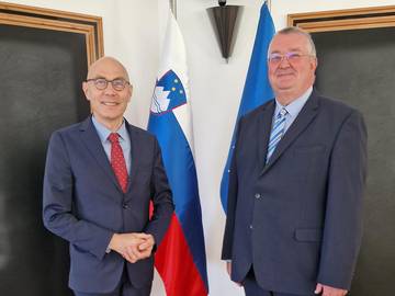 Volker Türk in Ivan Šelih stojita pred slovensko in evropsko zastavo