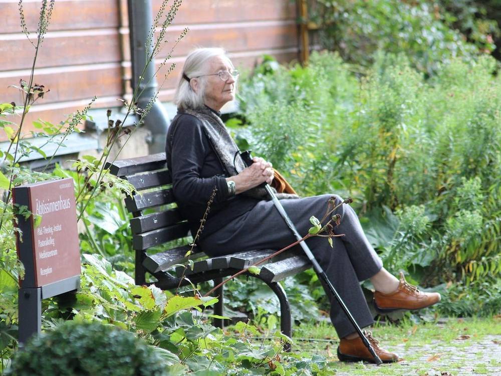 Starejša gospa sedi na klopi